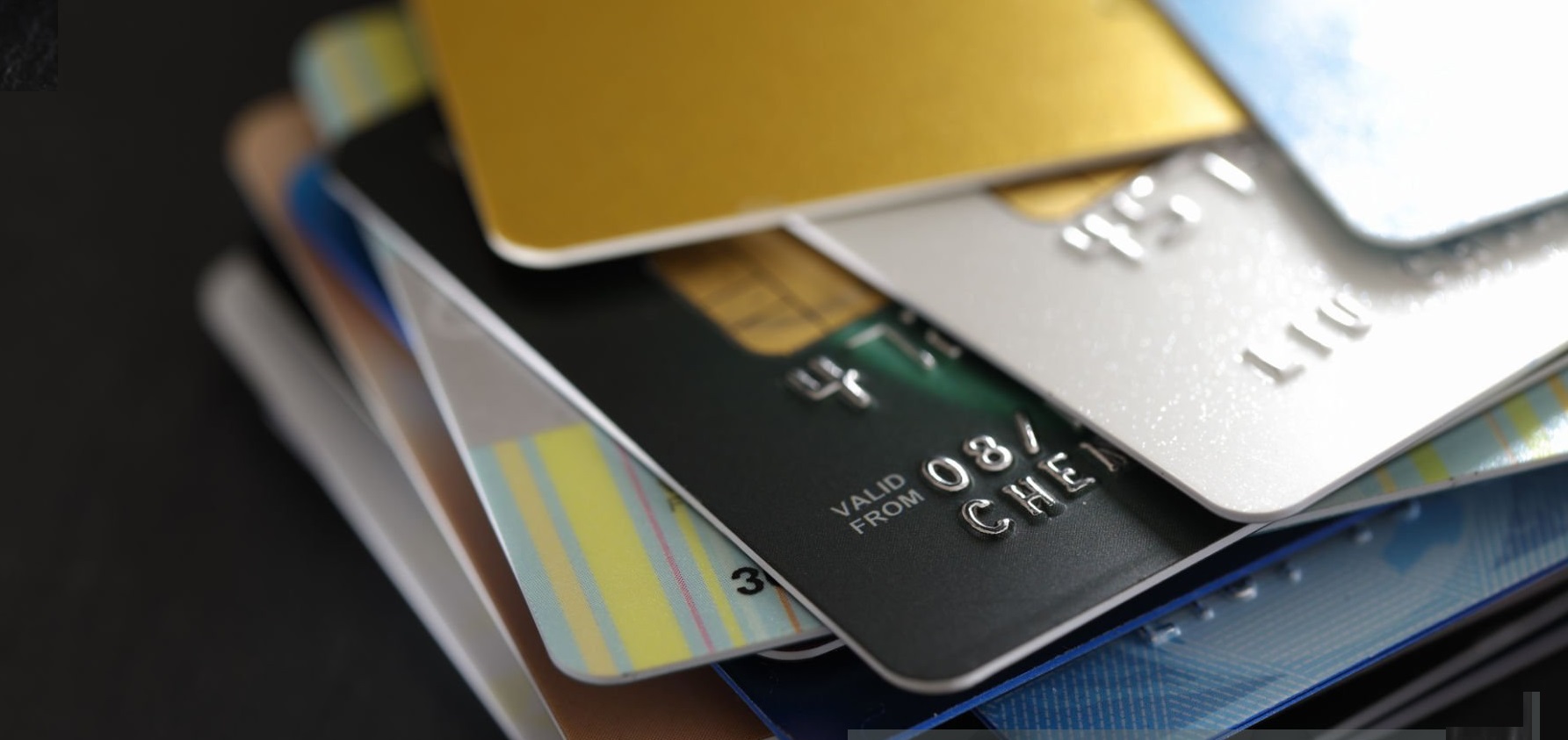 stack of multicolored credit cards on black background